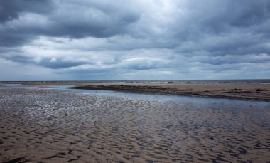 Bulutların yansıması bulutlu bir havada Jurmala 'da Baltık Denizi' nin kumlu kıyısında küçük bir lehman.