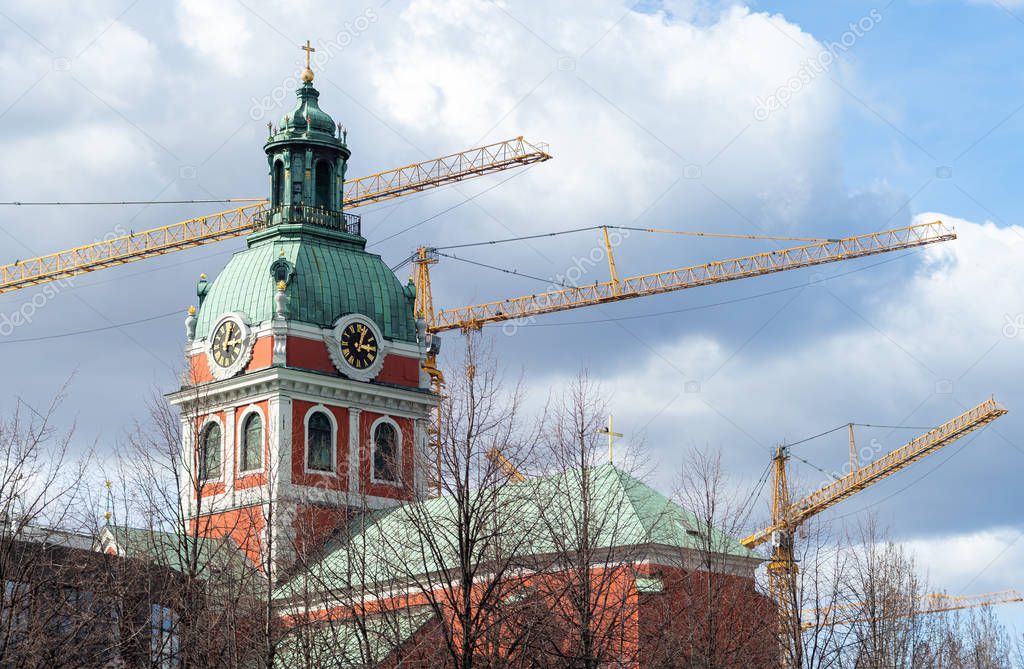 Construction cranes over the red Saint Jamess Church -Jakob kyrka in Stockholm.