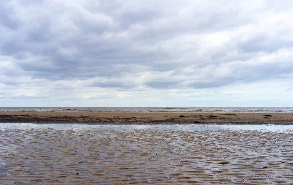 曇りの日にジュルマラのバルト海の砂浜の小さなリーマンの雲の反射 — ストック写真