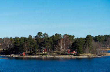 Baltık Denizi 'ndeki Stockholm takımadasının konut adasında geleneksel falun kırmızısına boyanmış resimli yazlıklar..