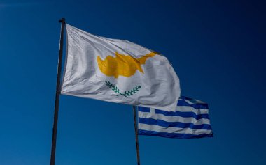 Kıbrıs Cumhuriyeti ve Yunanistan bayrakları mavi gökyüzüne karşı.