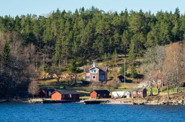 Baltık Denizi 'ndeki Stockholm takımadasının konut adasında geleneksel falun kırmızısına boyanmış resimli yazlıklar..