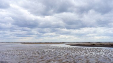 Bulutların yansıması bulutlu bir havada Jurmala 'da Baltık Denizi' nin kumlu kıyısında küçük bir lehman.