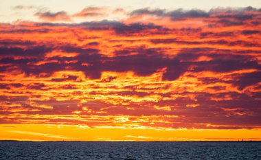 Clouds illuminated by the setting sun over the blue waters of the Baltic Sea.