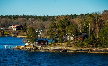 Baltık Denizi 'ndeki Stockholm takımadasının konut adasında geleneksel falun kırmızısına boyanmış resimli yazlıklar..