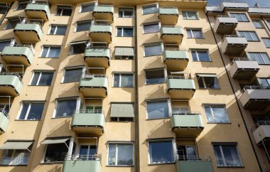 Küçük yeşil balkonlu sarı bina, güneş tarafından aydınlatılıyor.