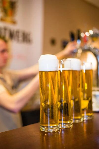 Barman pours foamy beer