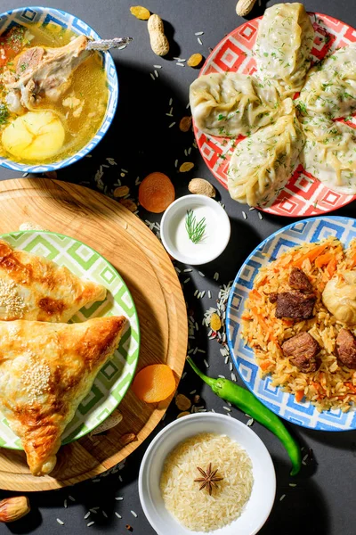 Dishes of Uzbek cuisine pilaf, shurpa, samsa, manti on black background top view — Stock Image Dishes of Uzbek cuisine pilaf, shurpa, samsa, manti on black background top view Royalty Free Stock Photos
