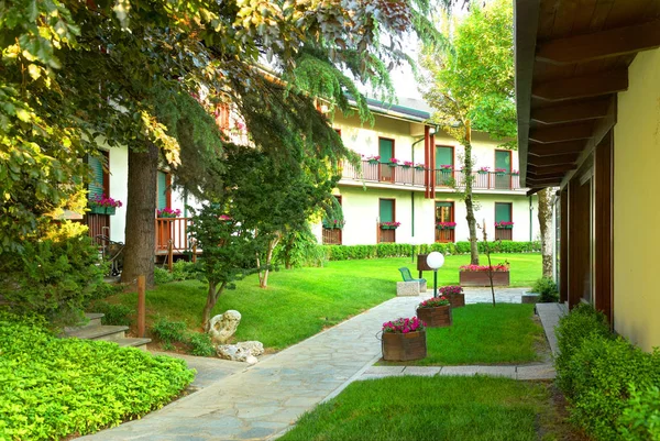 SAVIGLIANO, ITÁLIA, MAIO, 25, 2010: Pátio jardim interior do dia de verão de Grantbaita árvores do hotel flores ao lado do restaurante italiano. Exterior do hotel. Itália férias passeios famosos restaurantes hotéis — Fotografia de Stock