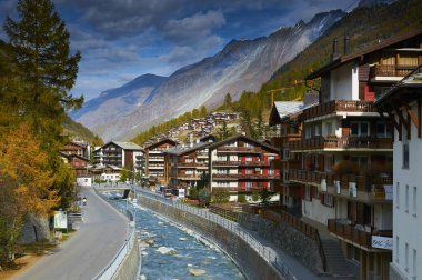 Zermatt, İsviçre, 20 Ekim 2010: Madde Vispa Nehri'nde köprü görünümünden Uferweg Caddesi üzerinde konut, otel ve Alp dağ. Klasik lüks Swiss cottage dağ evi. İsviçre tatil tatiller