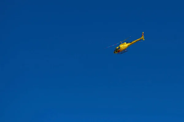 Helicóptero de passageiros turístico vermelho amarelo voando no céu azul sem nuvens. Helicóptero amarelo. Dia ensolarado de verão Alpine montanhas helicóptero passeios. Helicóptero ar um — Fotografia de Stock