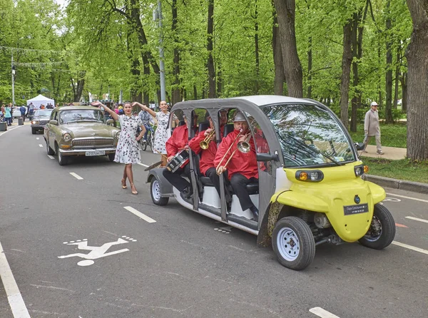 Moskou, 21 mei 2017: Retro auto parade buiten straat week eind tentoonstelling in Sokolniki stadspark. Retro oldtimers parade orkest en jonge meisjes lopen in vintage jurken. Weekend auto parade — Stockfoto