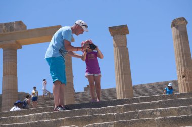 Rodos Adası, Lindos, Yunanistan, 22 Haziran 2013: teachs küçük kızı baba nasıl kamera ve fotoğrafları antik Yunan tapınağı kalıntıları Yunanistan adada Lindos şehir içinde. Aile turları.