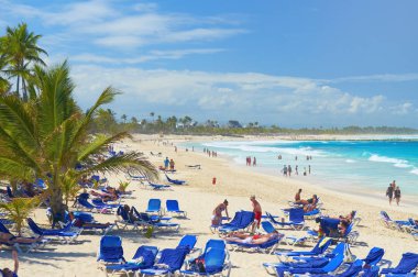 Güneş Baza sandalye ve tropikal Hindistan cevizi avuç içi tost rahatlatıcı turist Punta Cana, Dominik Cumhuriyeti, Şubat, 21, 2013: Atlantik Okyanusu kum plaj. Punta Cana tatil tatil turları seyahat spor
