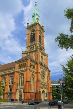 Dusseldorf, Almanya, Jun.13, 2010: Eski antik kırmızı Roma Katolik Kilisesi'nin çan kulesi ile tuğla ve yaz güneşli bir günde saat. Kırmızı turuncu kahverengi tuğla kilise katedral tapınak mimarisi dikey görünüm 