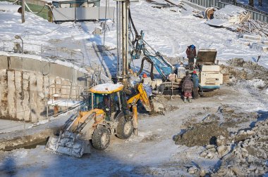 Moskova, 01 Şubat 2018: Kış görünümü üzerinde kirli ağır inşaat ekipman, araç ve işçilerin iş yerinde. Şantiye Delme işlemleri. Pis işleri inşaat alanında. İnşaat makineleri