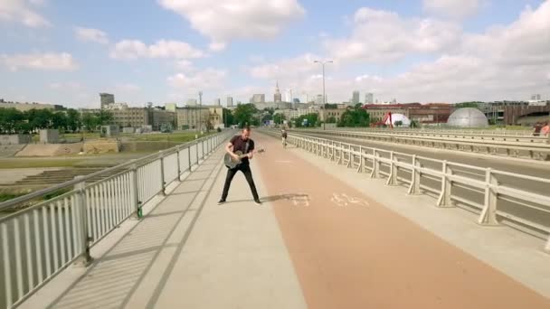 Гитарист, рок-музыкант, уличный музыкант на мосту. Стрельба с воздуха — стоковое видео