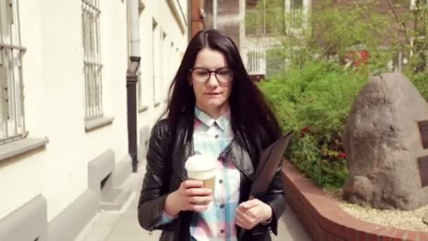 商务女士带眼镜 黑色皮夹克和咖啡离开办公室 — 图库视频影像