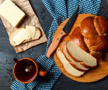 Ekmek, tereyağı ve çay karanlık bir arka plan üzerine dilimlenmiş. Üstten Görünüm