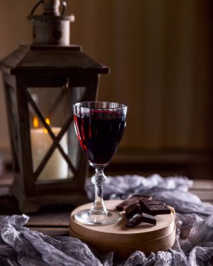 Bardak kırmızı şarap. Yakın çikolata kırık. Fener bir candl ile