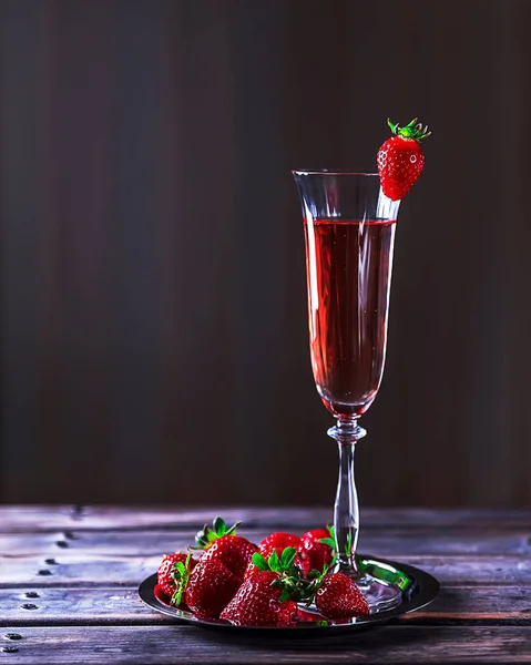 Copo de champanhe rosa e morangos em uma mesa de madeira — Fotografia de Stock