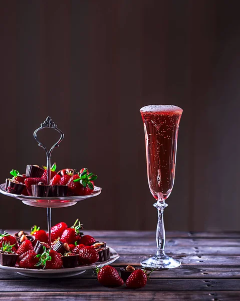 Sklenka růžového šampaňského na dřevěný stůl. Stojan s strawberri — Stock fotografie