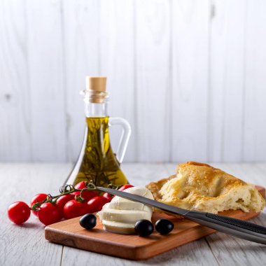 Zeytinyağı, domates, peynir ve ekmek masanın üzerine