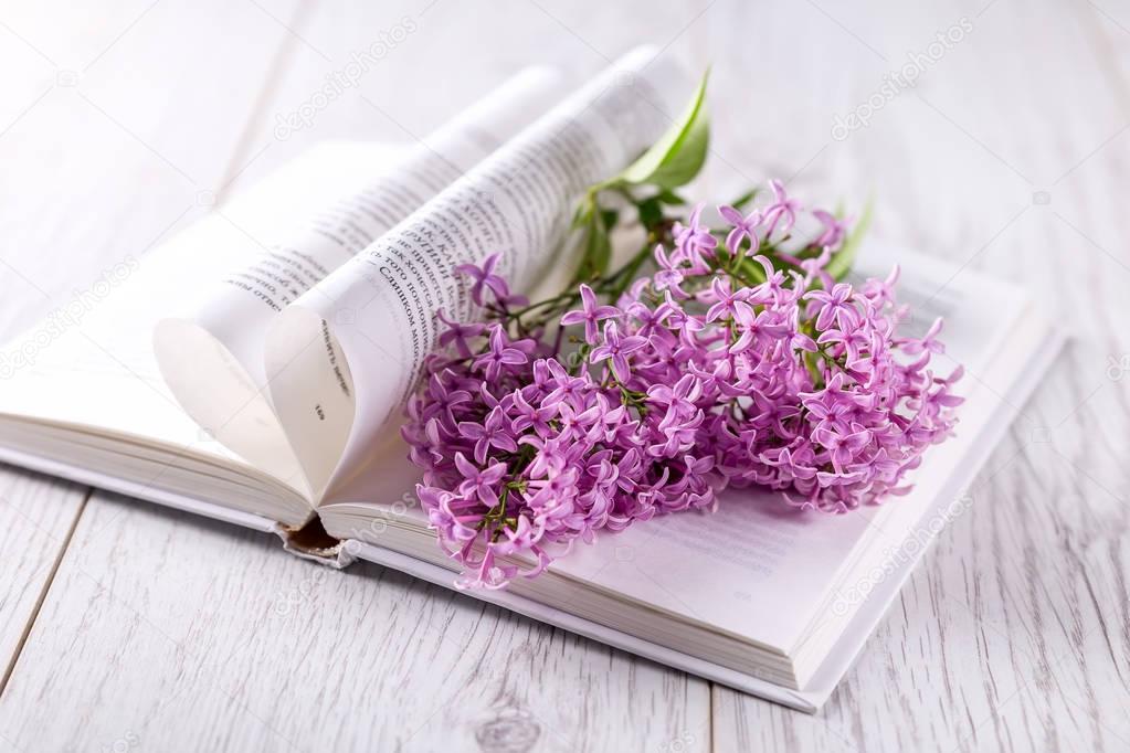 Lilac flowers on an open book on a light background