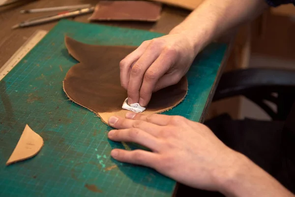作業机で天然皮革を染色するレザーマスターハンドのクローズアップ 本物の革を染色マスターの男性の手 ハンドメイド皮革製品製造業 — ストック写真