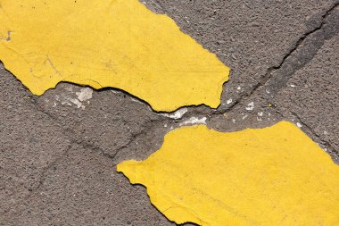 Kırık asfalt yolundaki sarı çizgi. Asfalt kabataslak yüzey arkaplanında çatlak.