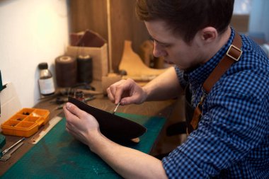 Usta, atölyesinde gelecekteki deri ürünlerinin desenlerini boyuyor. El yapımı deri ürünleri üretimi. Fotoğraf, dikiş, el işi, deri ürünleri, hobiler, el yapımı ürünler, kendi küçük otobüsleri için kullanılabilir.