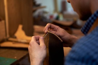 İleride gözlük takmak için kahverengi deri parçaları iğneyle diken zanaatkâr ellerinin yakın çekimi. Atölyede deri diken iğneli adam. Zanaatkar, iğne ve iplikle gözlük dikmek için deri çanta dikerken. Bu fotoğraf ne için kullanılabilir?