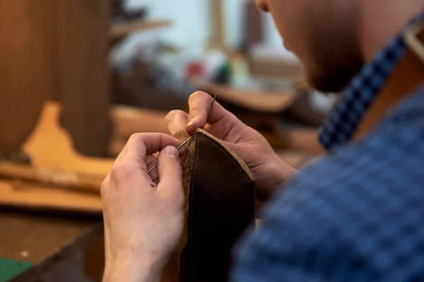 職人の手の閉鎖は メガネのための将来のケースのための針で茶色の革の部品を縫製 工房で針縫いの革を持った男 職人は茶色の革 針と糸で作業します 職人の小規模事業 — ストック写真