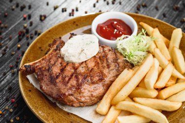 Orta nadir ızgara sığır eti biftek kahverengi plaka üzerinde ahşap siyah arka plan üzerine