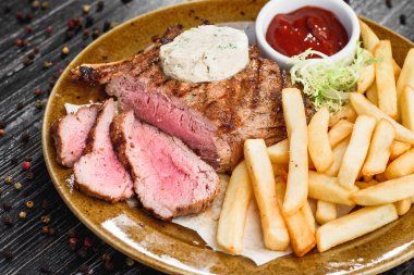 Orta nadir ızgara sığır eti biftek kahverengi plaka üzerinde ahşap siyah arka plan üzerine