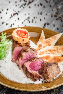 Orta nadir ızgara sığır eti biftek kahverengi plaka üzerinde ahşap siyah arka plan üzerine