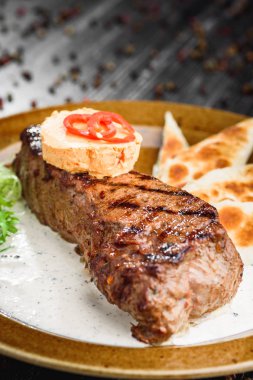 Orta nadir ızgara sığır eti biftek kahverengi plaka üzerinde ahşap siyah arka plan üzerine
