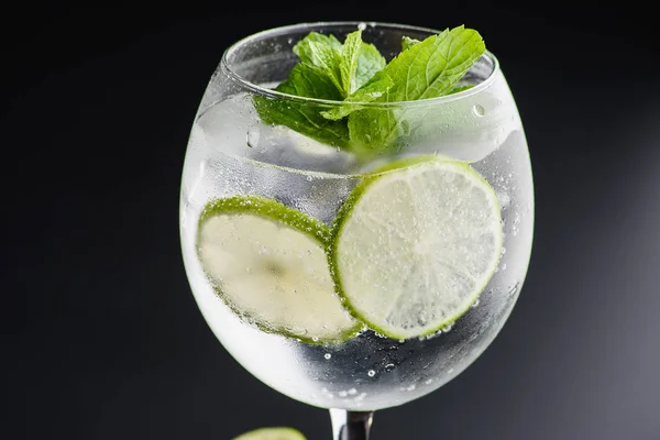 Cocktail "gin and tonic" on a dark uniform background with lime — Stock Photo, Image