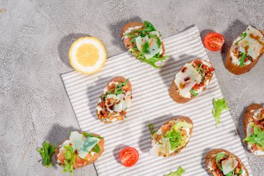 Gri beton veya taş zemin üzerine somon balığı, domates, peynir ve fesleğen pesto ile İtalyan bruschetta.