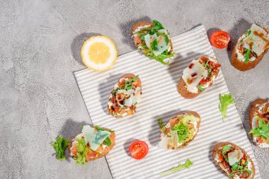 Gri beton veya taş zemin üzerine somon balığı, domates, peynir ve fesleğen pesto ile İtalyan bruschetta.