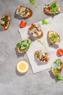 Gri beton veya taş zemin üzerine somon balığı, domates, peynir ve fesleğen pesto ile İtalyan bruschetta.