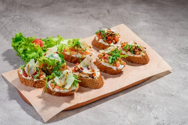 Gri beton veya taş zemin üzerine somon balığı, domates, peynir ve fesleğen pesto ile İtalyan bruschetta.