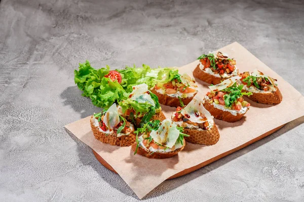 Gri beton veya taş zemin üzerine somon balığı, domates, peynir ve fesleğen pesto ile İtalyan bruschetta.