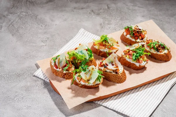 Gri beton veya taş zemin üzerine somon balığı, domates, peynir ve fesleğen pesto ile İtalyan bruschetta.