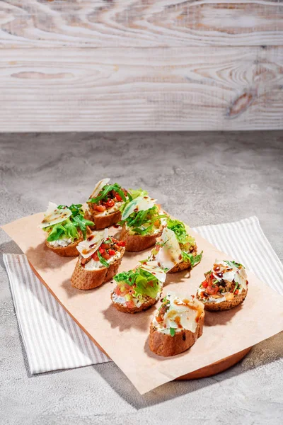 Bruschetta italiana con pesto de salmón, tomate, queso y albahaca sobre un fondo gris de hormigón o piedra . — Foto de Stock