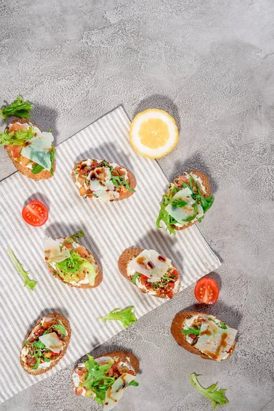 Bruschetta italiana con pesto de salmón, tomate, queso y albahaca sobre un fondo gris de hormigón o piedra . — Foto de Stock