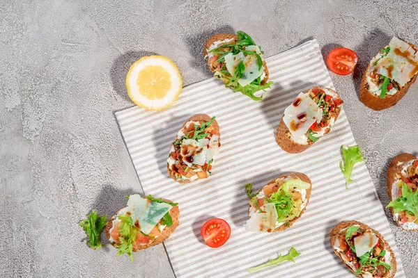 Gri beton veya taş zemin üzerine somon balığı, domates, peynir ve fesleğen pesto ile İtalyan bruschetta.