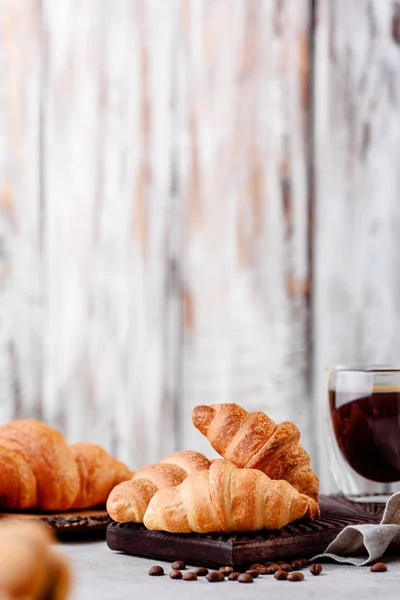 Croissants en platos de madera con café sobre un fondo claro — Foto de Stock