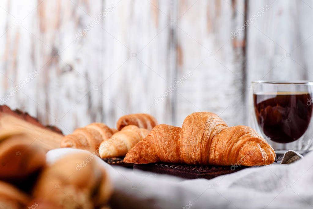 croissants in wooden plates with coffee on a light background