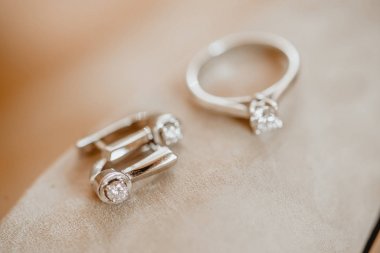 Güzel bir gümüş yüzük ve bej renkli arka plan üzerinde bir elmas küpe.